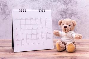 nallebjörn med kalender på bord i trä. alla hjärtans dag firande foto