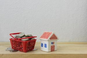 mynt i en korg röd och hus modell för pengar koncept foto