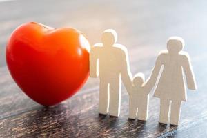 rött hjärta och ikon familj på trä skrivbord. sjukförsäkring koncept foto