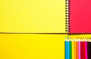 regnbågspalett av färgpennor med en spiral anteckningsbok på en gul bakgrund, mock up, platt lay. tillbaka till skolan, elevrekrytering, konstnär, ritlektioner. kopieringsutrymme. brevpapper för kreativitet foto
