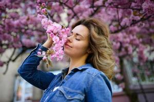 vårporträtt. vacker ung kvinna med sakura. utomhus- foto