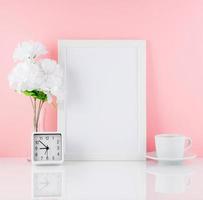 tom vit ram, blomma, klocka, kopp kaffe eller te på ett vitt bord mot den rosa väggen med kopieringsutrymme. håna. foto