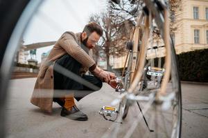 man kontrollerar hjul på cykel. reparera cykel på gatan. foto