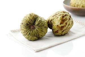 färskt socker äpple frukt eller vaniljsås äpple eller annona cherimoya, godis i korg med vit bakgrund isolerad foto