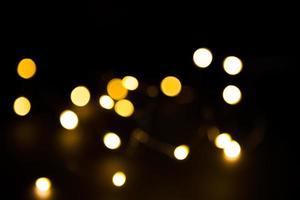 gult och guld ljus krans i en oskärpa på en svart bakgrund. bokeh av flygande cirklar i oskärpa. festlig atmosfär av jul och nyår. fira bakgrund foto