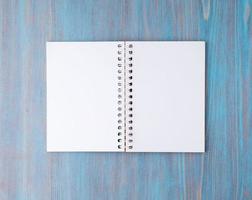 öppen anteckningsbok på våren med vitt papper för anteckningar och ritning. ljus bakgrund, blått trä, ovanifrån. foto