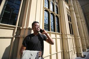 afroamerikansk man har roligt att gå i stadens centrum - glad ung kille som njuter av tiden en solnedgång utomhus - tusenårig generation livsstil och positiva människor attitydkoncept foto