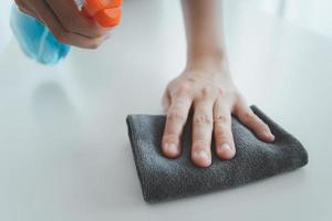 oigenkännlig husfru som rengör bordsytan med hjälp av desinfektionsmedel. foto