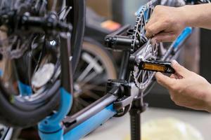 cykelmekaniker reparerar hopfällbar cykel i verkstad. justera cykelpedaler. cykel underhåll och reparation koncept foto