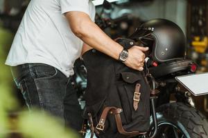 förare installera en motorcykelsadelväska eller sidoväska på bagagehållare vintage motorcykel motorcykel resor koncept. selektiv fokusering foto