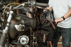 ryttare tar kläderna ur sidoväskan eller sadelväskor på motorcykel efter resa, motorcykelresekoncept. selektiv fokusering foto