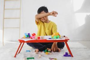 pojke som gråter när han leker ensam hemma. traumatisk upplevelse i barndomen, psykologi, psykologisk, aspergers syndrom, aspergers sjukdom, autism, autism. foto