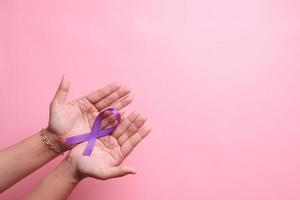 hand som håller lila band för Alzheimers sjukdom, cancer i bukspottkörteln, epilepsimedvetenhet, världscancerdagen foto