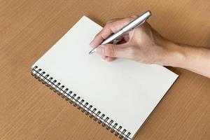 man hand med penna förbereda att skriva på anteckningsboken foto