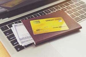 kreditkort och pass nära bärbar dator på bordet. online biljettbokningskoncept foto