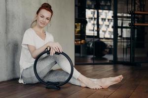 ung sportig kvinna poserar med pilates toning ring foto
