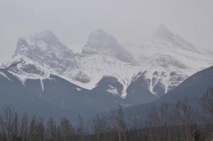 snötäckta klippiga berg med disig grå himmel foto
