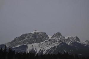 snötäckta klippiga berg med disig grå himmel foto