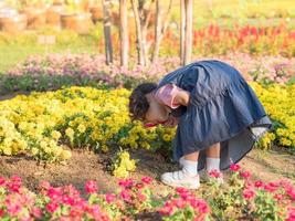 flickan som står på fältet och använder ett förstoringsglas för att titta på blommorna foto