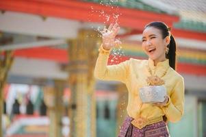 vackra thailändska tjejer i thailändska kostymer håller vattenskålar och strö vatten med händerna på songkran festival foto