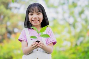 bild asiatisk liten flicka som håller en planta i handen foto