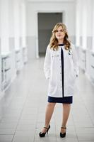 porträtt av en ung attraktiv läkare i vit rock med stetoskop poserar på sjukhuset. foto