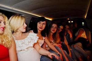 underbara tjejer har kul när de sitter inne i den lyxiga limousinen på möhippa. foto