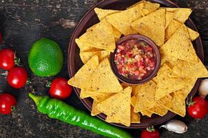 mexikanska nachochips och salsa dopp i skål på trä bakgrund foto