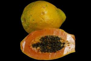halv snitt av färsk mogen papaya med frön isolerade på mörk bakgrund. selektiv fokusering. foto
