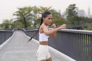 ung fitness kvinna i sportkläder boxning i stadsparken, hälsosam och livsstil. foto