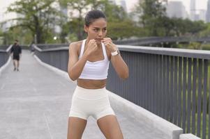 ung fitness kvinna i sportkläder boxning i stadsparken, hälsosam och livsstil. foto