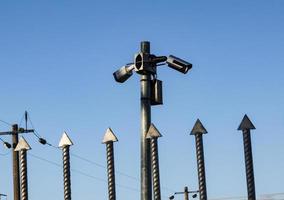 videokameror över järn staket spikar på blå himmel foto