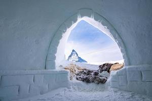 snöklädd matterhorn topp mot himlen sett genom ingången till igloo i alperna foto