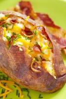 bakad potatis med bacon, ost och gräslök foto