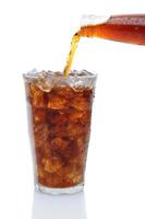 cola hälla från flaskan i ett glas is