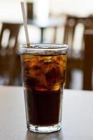 glas cola med is på ett bord