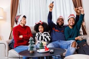 afrikansk amerikansk familj i jultema. lycklig familj har kul att sitta tillsammans i soffan hemma. foto