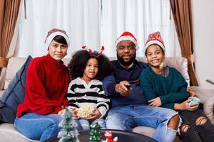 afrikansk amerikansk familj i jultema. lycklig familj har kul att sitta tillsammans i soffan hemma. foto