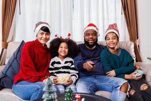 afrikansk amerikansk familj i jultema. lycklig familj har kul att sitta tillsammans i soffan hemma. foto