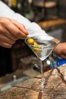 barman på jobbet, förbereder cocktails. förbereda martini med oliver. foto