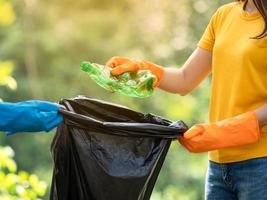 frivilliga kvinnor samlar in plastvattenflaskor i parken, från människor som vägrar att slänga i soporna i en påse för återvinning foto