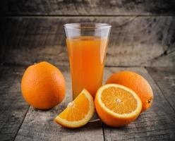 apelsinjuice och färska apelsiner på trä foto