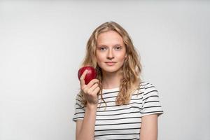 porträtt av ung leende kvinna med rött äpple. fräscht ansikte, naturlig skönhet foto