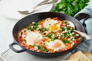 shakshouka, ägg pocherade i tomatsås, olivolja. medelhavskusine. foto