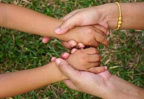 mammas hand håller en liten flickas hand på bokehbakgrund. kärlek och familj koncept. foto