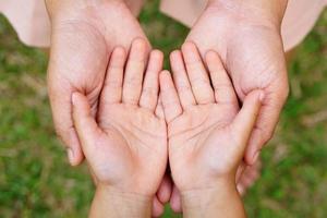 mammas hand håller en liten flickas hand på bokehbakgrund. kärlek och familj koncept. foto