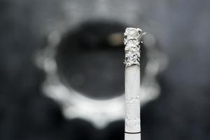 närbild av brinnande cigarett på mörk bakgrund foto