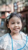 porträtt av lycklig charmig 4 år gammal söt asiatisk flicka, litet förskolebarn med leendekänsla i ansiktet foto