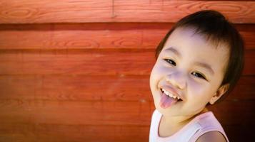 asiatisk flicka litet barn som sticker ut tungan och tittar på kameran. foto