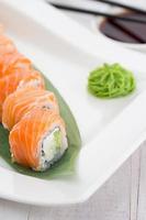 laxsushirulle på en vit platta med wasabi foto